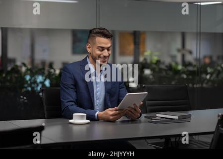Smiling handsome middle eastern entrepreneur using digital tablet Stock Photo
