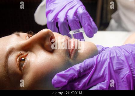 Lip shape correction procedure in a cosmetology salon. The specialist makes an injection on the lips of the patient. Lip augmentation. Stock Photo