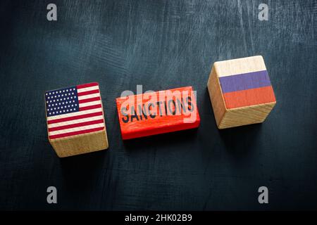 Wooden cubes and flags of USA and Russia and word sanctions. Stock Photo