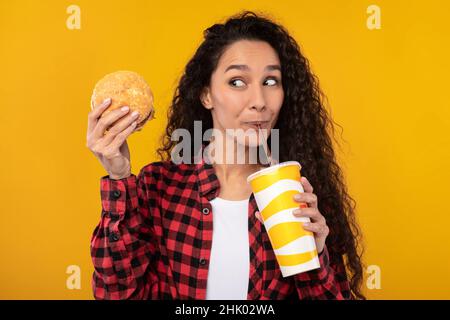 Funny Young Lady Holding Burger And Drink Stock Photo