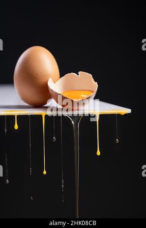 Fresh egg spilling out on  black background. Stock Photo