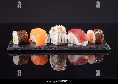 Assorted sushi served on slate plate on dark background. Japanese food. Stock Photo