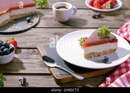 Slice of classical cheesecake served on white plate on wooden table. Selective focus. Stock Photo