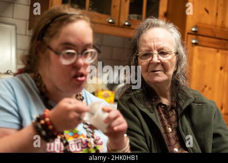 Hakendover, Flemish Brabant, Belgium - 09 20 2021: Disabled 39 year old woman and her 83 year old mother having fun in the kitchen at home.
