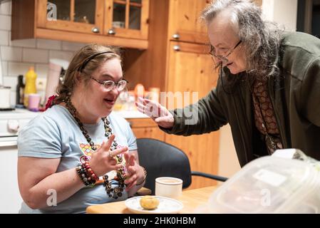 Hakendover, Flemish Brabant, Belgium - 09 20 2021: Disabled 39 year old woman and her 83 year old mother having fun in the kitchen at home.