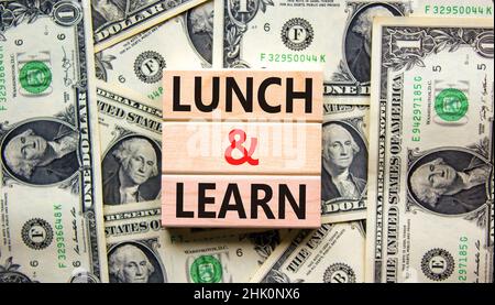 Lunch and learn symbol. Concept words Lunch and learn on wooden blocks. Beautiful background from dollar bills. Copy space. Business, educational and Stock Photo