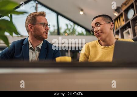 Focused businesspeople collaborating on new project two young entrepreneurs using laptop while working together in modern workspace young adult busine Stock Photo