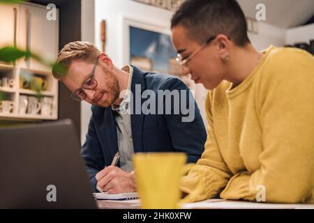 Focused couple of diverse businesspeople doing paperwork together while working in casual cozy home office. Stock Photo