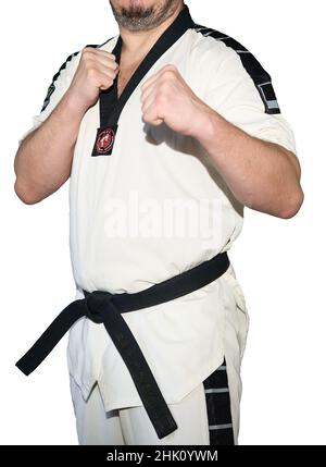 Man in taekwondo martial arts uniform in fighter stance isolated on the white background. Stock Photo