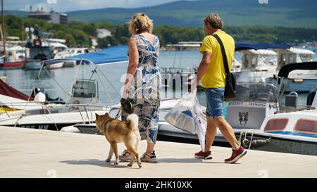 Couple with dog on the promenade in the port of the town of Krk on the Adriatic Sea in Croatia Stock Photo