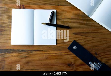 paper notebook, fountain pen and ink on wooden table - flat lay Stock Photo