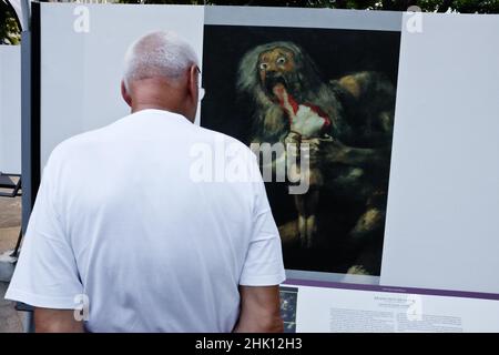 A man watching a copy of 'Saturn devouring his child', by Goya, in an street exhibition in Makati, Manila, Philippines. Stock Photo