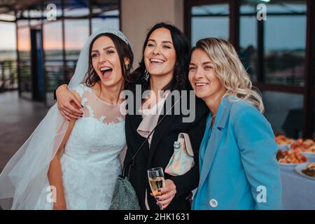 Wedding. bride with guest friends cuddled and laugh drinking champagne Yaremche, Bukovel, Ukraine - January 10, 2022 Stock Photo