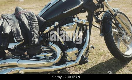 Chrome motorcycle. Stock. Side view of new black motorcycle with chrome details and clothes of motorcyclist lying on it. Chrome details motorcycle ref Stock Photo