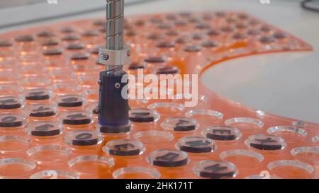 Test Tube Closing Production Machine. HDR. Testing of robotic machine for analysis with laboratory test tubes. Robotic machine transfers traffic jams Stock Photo