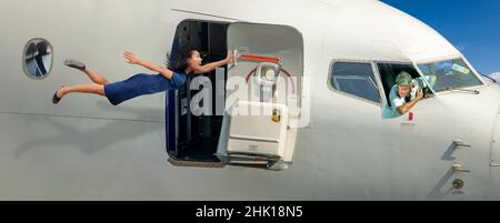 A stewardess is holding the open door of a flying plane Stock Photo