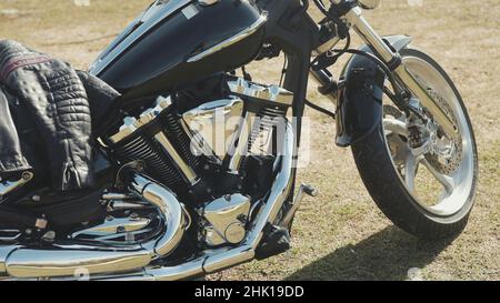 Chrome motorcycle. Stock. Side view of new black motorcycle with chrome details and clothes of motorcyclist lying on it. Chrome details motorcycle ref Stock Photo