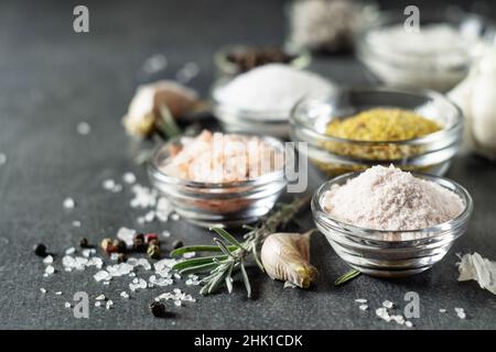 Different types of salt and culinary spices in glass plates on a dark background Stock Photo