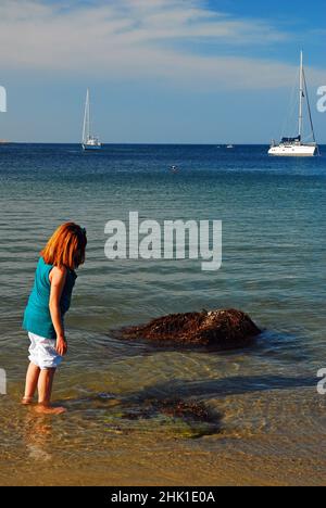 A young woman wades in the waters on the New England coast