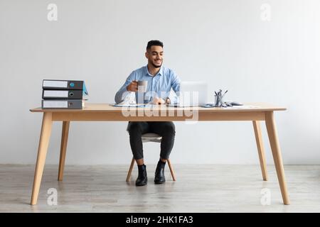 Arab man using laptop sitting at desk in office Stock Photo