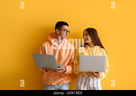Young couple with laptops on yellow background Stock Photo