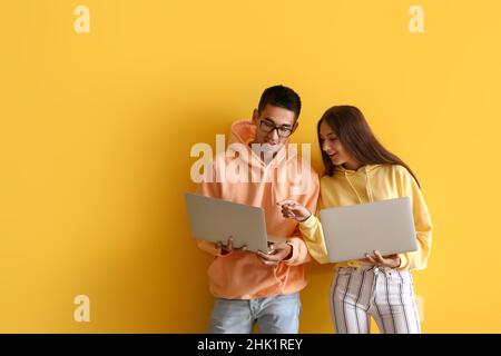 Young couple using laptops on yellow background Stock Photo