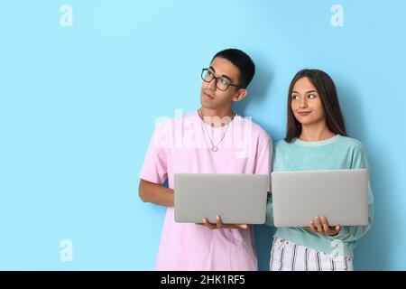 Young couple with laptops on blue background Stock Photo