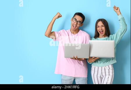 Happy young couple with laptops on blue background Stock Photo