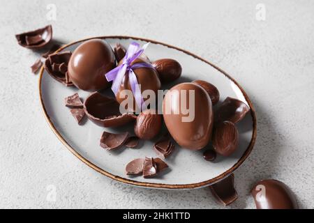 Plate with chocolate Easter eggs on light background Stock Photo