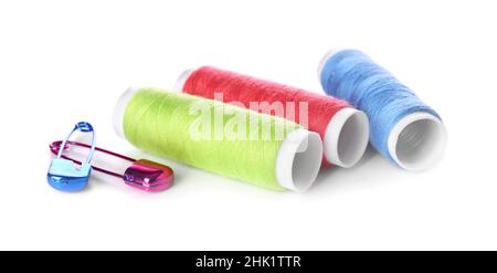 Multicolored thread spools and safety pins on white background Stock Photo