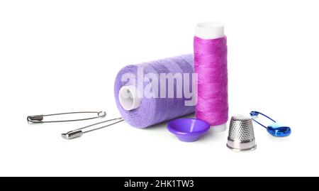 Thread spools, button, thimble and safety pins on white background Stock Photo