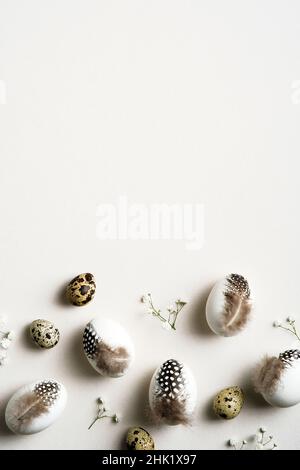 Happy Easter vertical flat lay composition with Easter eggs decorated feathers and gypsophila flowers. Top view. Happy easter card design. Stock Photo
