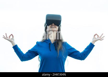 A woman smiling and doing yoga with vr glasses. Stock Photo