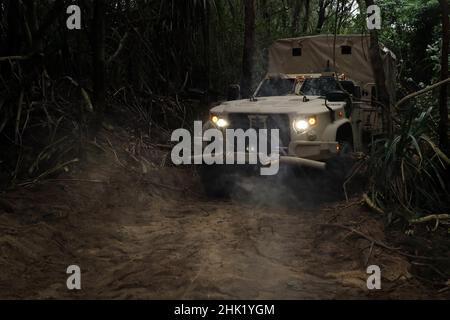 A Joint Light Tactical Vehicle travels through an artificial corridor created by combat engineers from Alpha Company, 3rd Landing Support Battalion, Combat Logistics Regiment 3, at Henoko Beach, Okinawa, Japan, Jan. 24, 2022. 3rd LSB conducted a battalion field exercise to train core mission essential tasks and rehearse emerging warfighting concepts in preparation for future exercises and operations. 3d MLG, based out of Okinawa, Japan, is a forward-deployed combat unit that serves as III MEF’s comprehensive logistics and combat service support backbone for operations throughout the Indo-Pacif Stock Photo