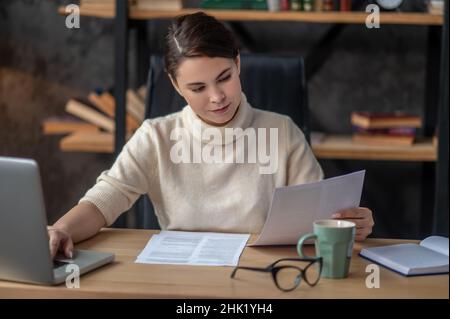 Focused female reading a contract at the writing table Stock Photo