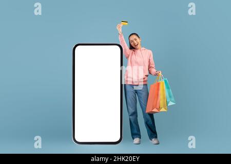 Emotional pretty asian lady with purchases and credit card Stock Photo