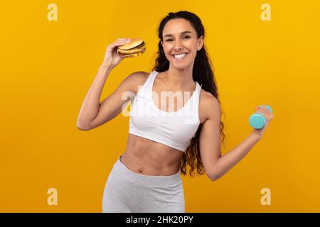 Funny Hungry Lady Holding Burger And Dumbbell Stock Photo