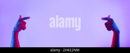 Unrecognizable young black man pointing at empty space in neon light, banner design Stock Photo