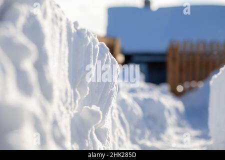 A man dug a passage through a lot of snow. Clearing snow to the house and fence after a big snowfall in winter. Stock Photo