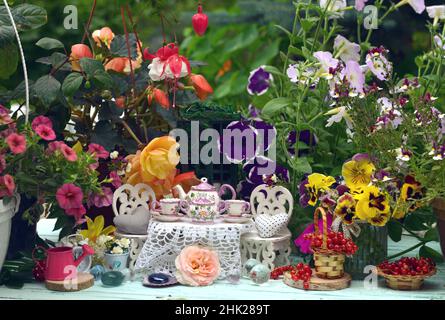 Tiny adorable table and chairs for tea party with flowers and berries.  Fairies in the garden. Lovely fable still life for greeting cards, wedding or Stock Photo