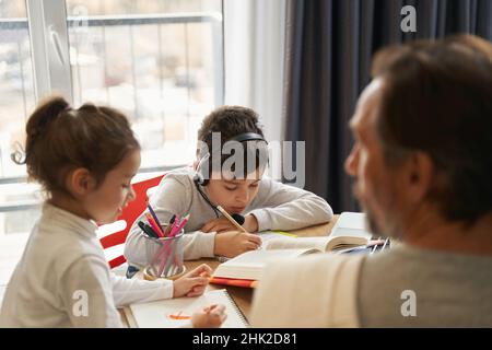 Boy in headset doing homework in the kitchen Stock Photo