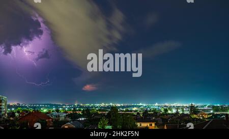 Thunderstorm over the city at night, bright lightning among dense clouds Stock Photo