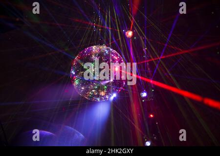 Mirrored Disco Ball and bright beams at the night party. Party attribute reflects Lazer lights. Abstract background with defocused rays. Night club atmosphere. Installation at Vilnius light festival Stock Photo