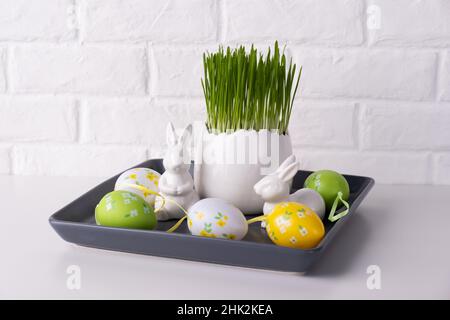 Home easter decor. Green oats, decorative rabbits and eggs Stock Photo
