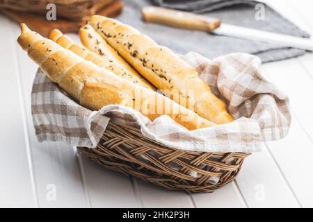 Baked croissant in basket. Crispy bun roll on a white table. Stock Photo