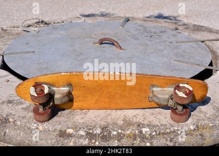 Old wooden 70's skateboard on a skatepark Stock Photo