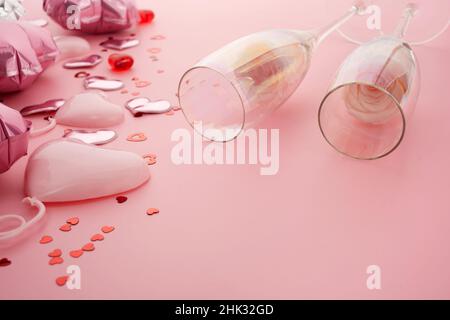 Valentines day pink background with two champagne glasses, hearts and roses. Stock Photo