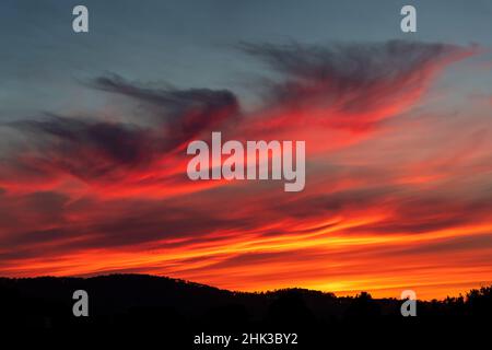 Deep, intense sunset colors in the clouds over the hills in the west Stock Photo