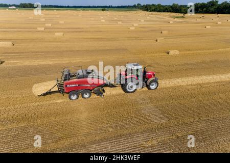 Aerial view of large square bales of wheat straw in field and tractor baling straw, Clay County, Illinois Stock Photo