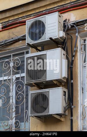 Three white air conditioners with wires on the facade of an old house (St. Petersburg, Russia) Stock Photo